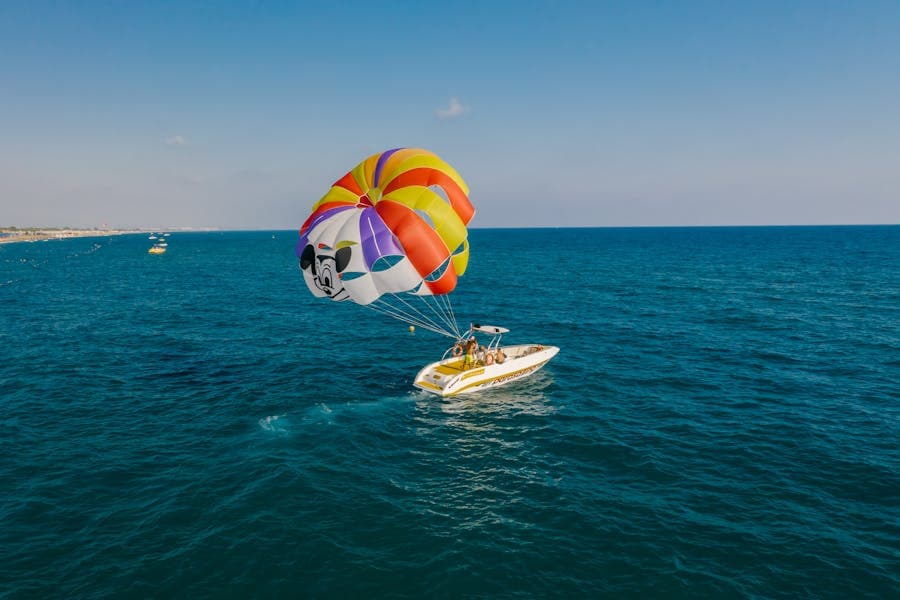 Parasail rising above turquoise coastal water.
