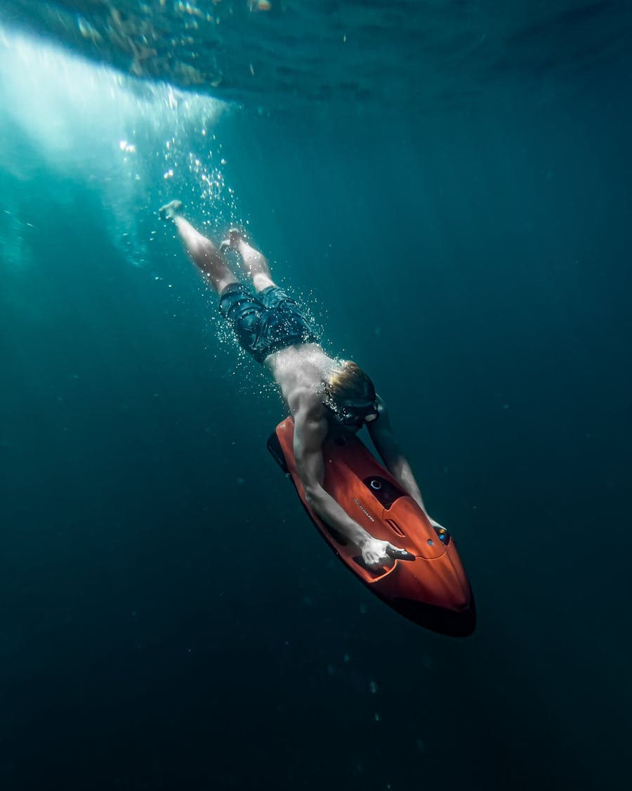 Free diver gliding underwater with an electric scooter.