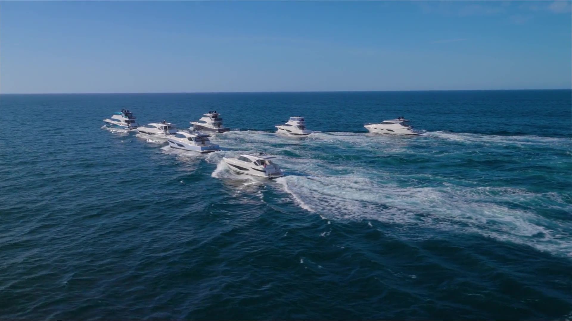 A fleet of luxury yachts at anchor on warm Hawaiian water.